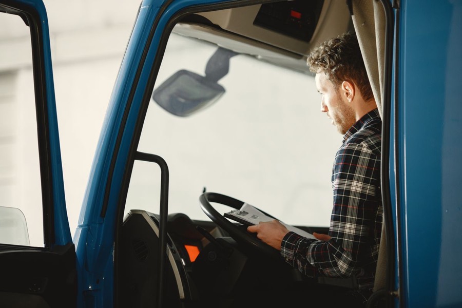 A trucking business owner reviewing paperwork at the wheel